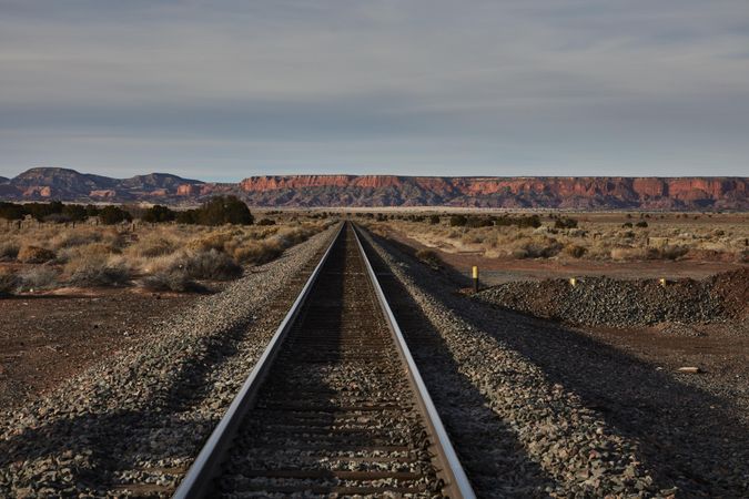 Train tracks with red rocks in the distance