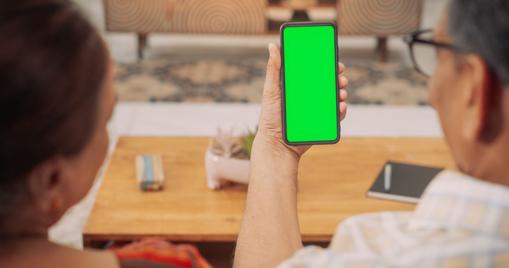 Over the Shoulder Mature Indian Couple Using Smartphone with Green Screen
