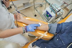 Hand of medical worker putting white cotton on arm of patient