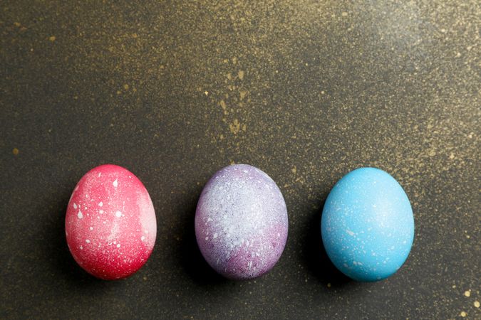 Decorated eggs on golden background. Space for text. Top view