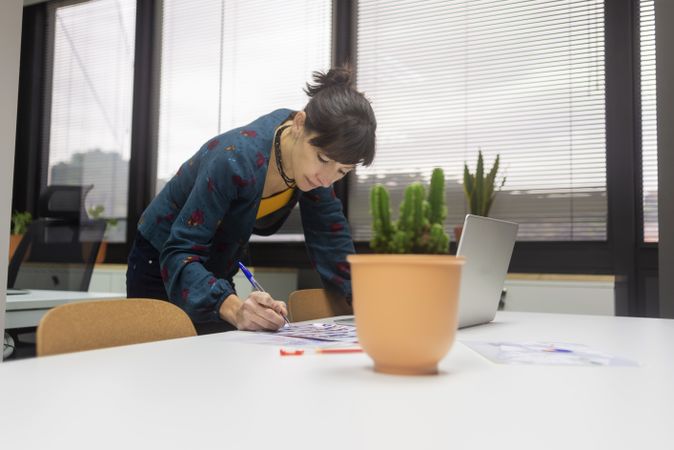female working with documents while standing at desk in modern office