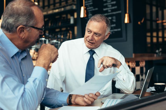 Two business partners reviewing documents at a coffee shop