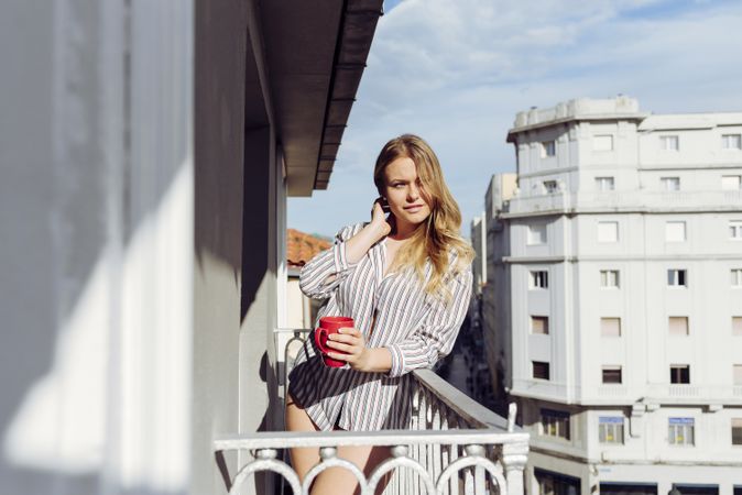 Young cheerful female with cup on terrace