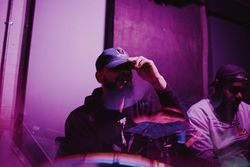 Young bearded man pulling down baseball cap brim in abstract magenta double exposure