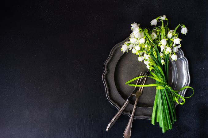 Top view of table setting for spring dinner with flowers on grey plate with copy space