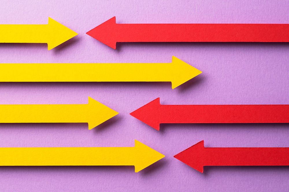 Yellow and pink paper arrows going in opposite directions