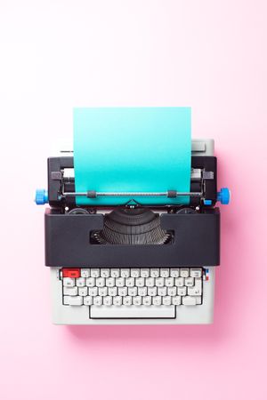 Typewriter with aqua paper over pink background