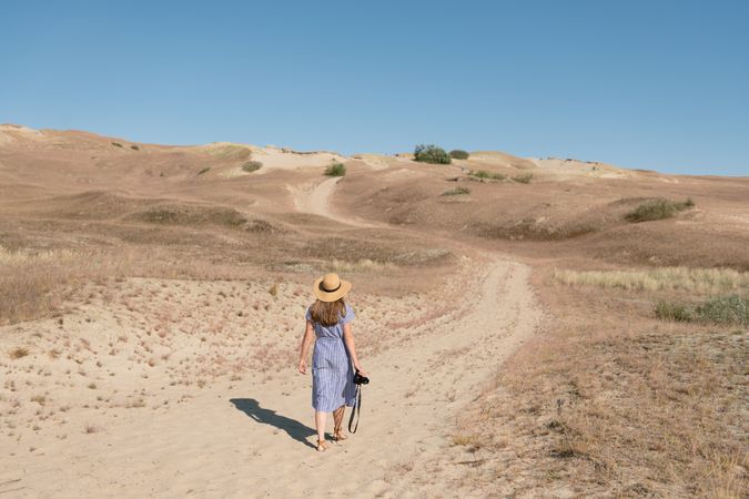 Young female photographer walking on dry field
