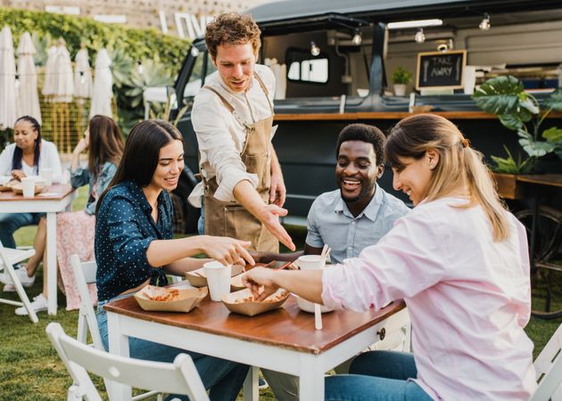 Multiracial people having fun eating at food truck outdoor