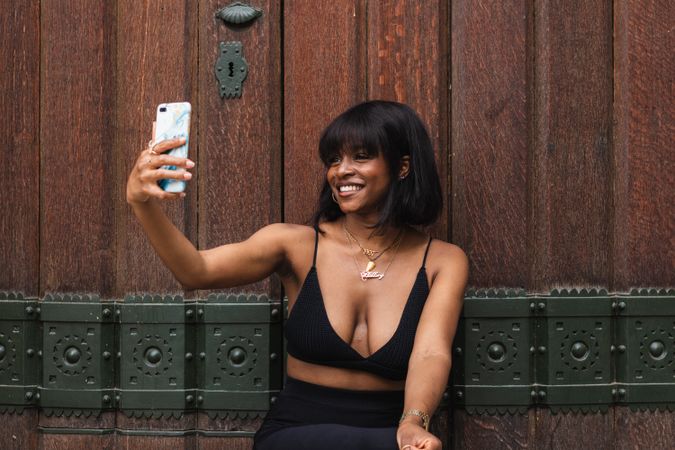 Cheerful Black woman taking selfie on smartphone