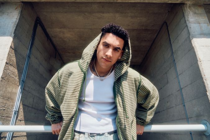 Male model in striped hoodie holding onto railing
