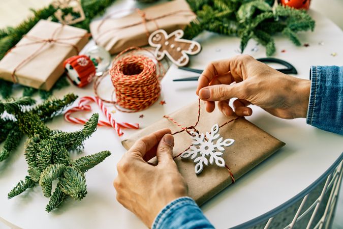 Anonymous person tying Christmas gift box on decorated table