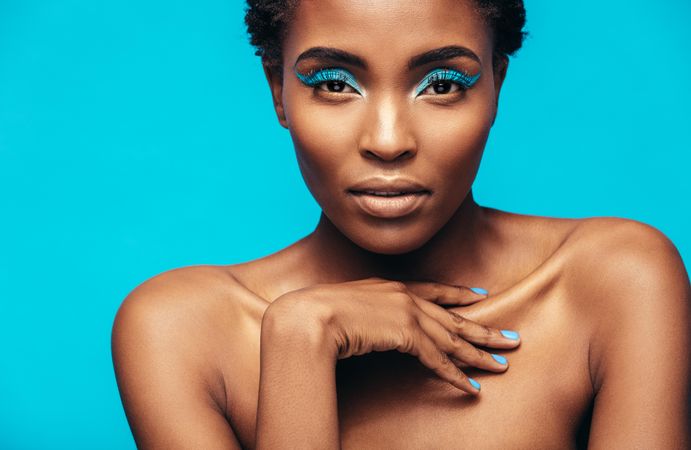 Close up of sensual woman wearing vivid makeup against blue background