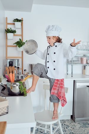 Shocked boy in cook uniform in kitchen