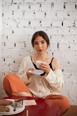 Peaceful woman drinking coffee while resting at home