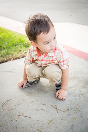 Boy reaching down to ground at the Park.