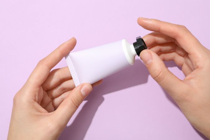 A jar of hand cream on a light, purple background.