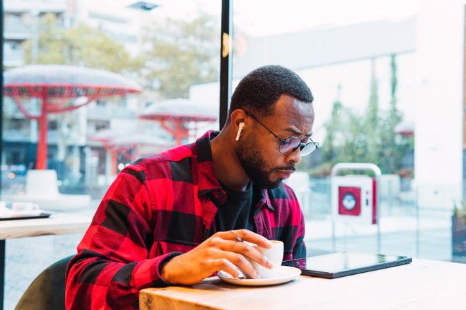 Black man using tablet while drinking coffee in cafe