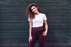 Happy Arab woman with curly hair standing outside of metal security doors