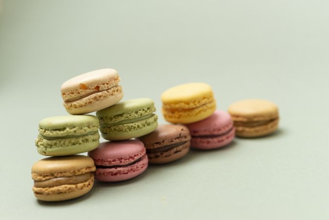 Pile of sweet pastel macaroons over a green background, with space for text