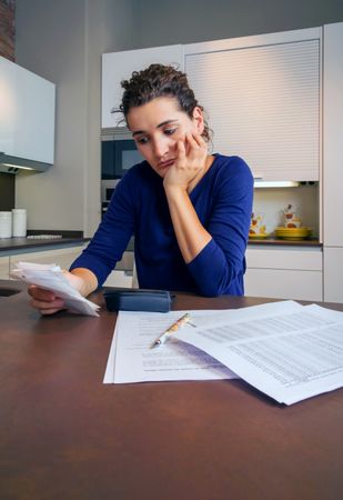 Woman reviewing bills at kitchen counter