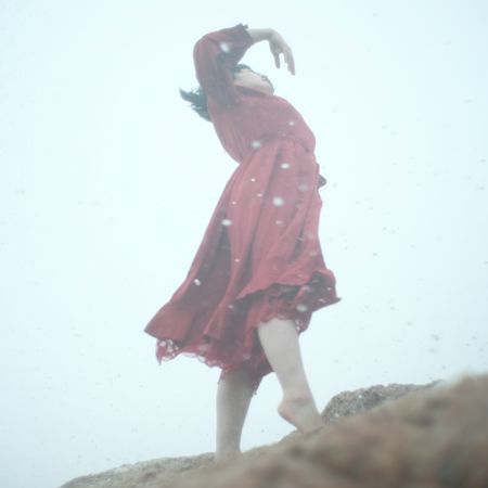 Woman in red dress dancing on beach