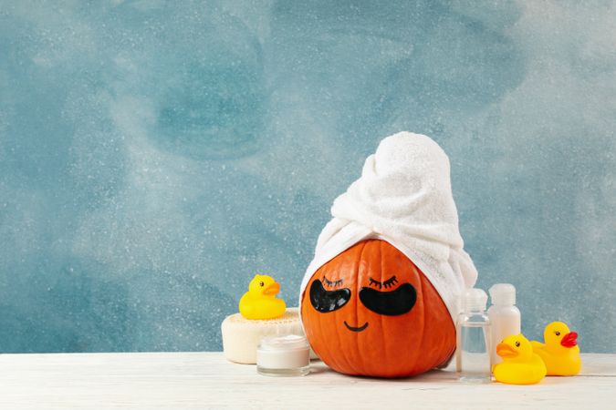 Skincare accessories and pumpkin with eye patches on blue background
