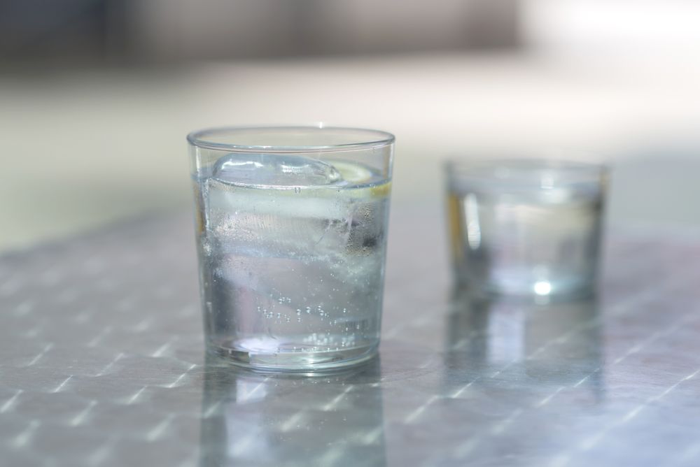 Two glasses of water with ice on a metallic table outdoors