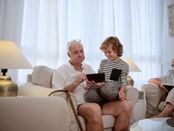 Grandfather browsing tablet with grandson
