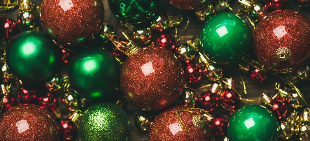 Close up of tree ornaments, large and small red, green and gold baubles, wide composition