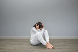 Unrecognizable woman holding head sitting on floor