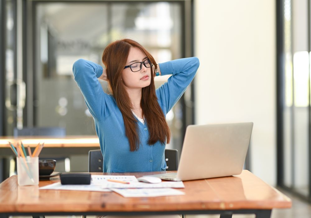 Asian woman wearing glasses with closed eyes relieves fatigue from work.