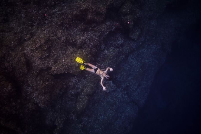 Unrecognizable man in flippers swimming under dark water