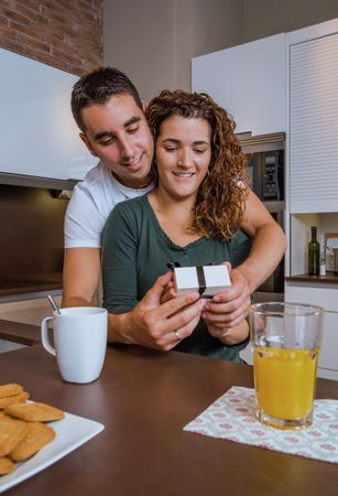Excited woman receiving giftbox over breakfast