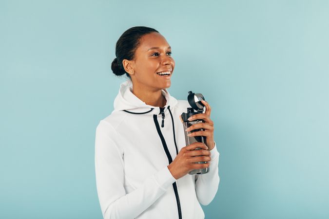 Smiling fit Black woman with water bottle on blue background