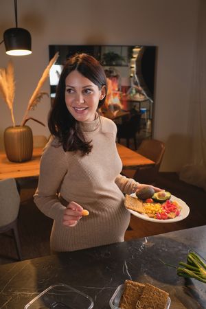 Smiling pregnant female with plate of healthy food