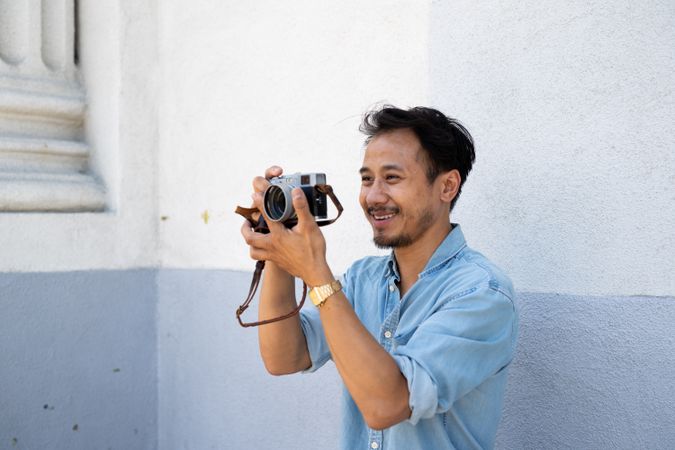 Asian photographer smiling and holding a camera away from face