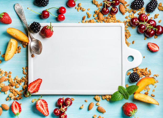 Fresh fruit arranged around cutting board with copy space