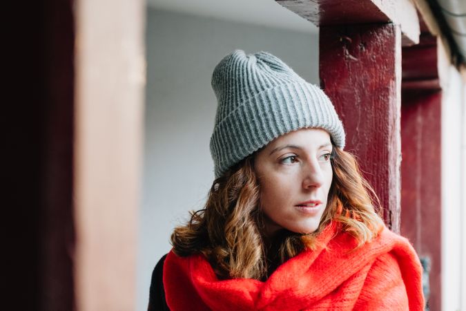 Positive woman in warm wear near house