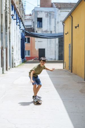 Front view of cheerful skater boy riding on the street on a sunny day