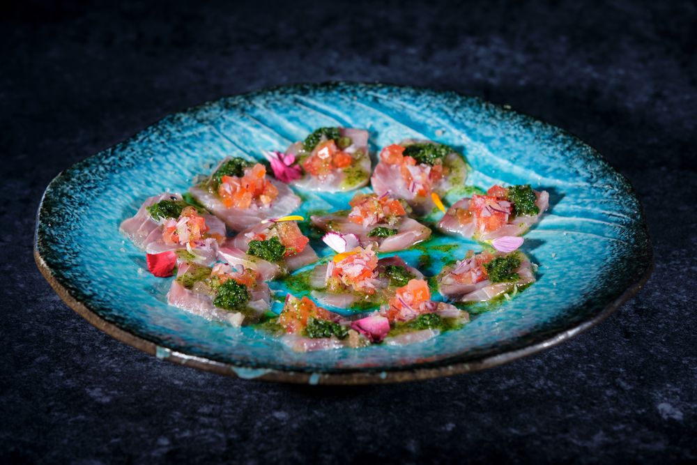 Plate with delicious fish dish on marble surface