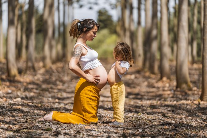 Pregnant mother and little daughter having fun in park