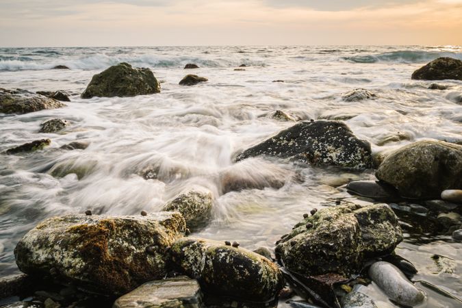 Stony seashore and waves at beautiful sunset