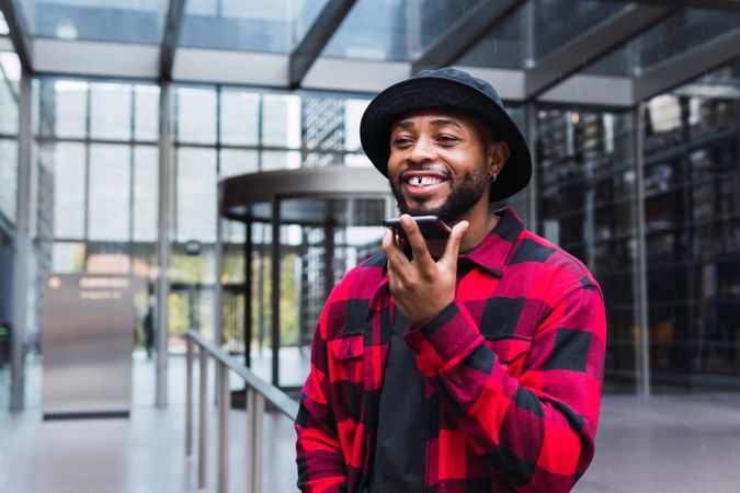 Cheerful Black man talking on smartphone on street