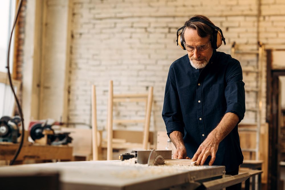 Older male in hearing protecting working on electric saw