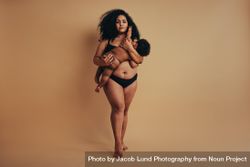 Strong body positive woman standing and breastfeeding her  child 433x14