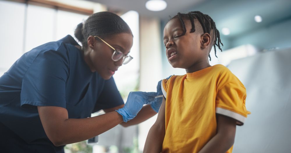 Female Black Nurse Is Performing Injection. Professional Woman Being Careful and Gentle To Ease The Pain