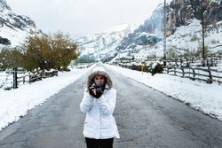 Content woman taking picture in snowy mountains