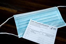 Medical mask and vaccination card laying on table