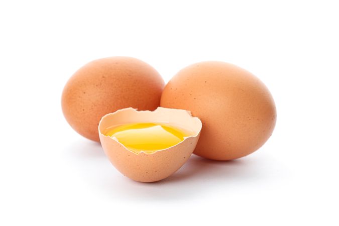 Chicken eggs and half broken egg with yolk  isolated on blank background